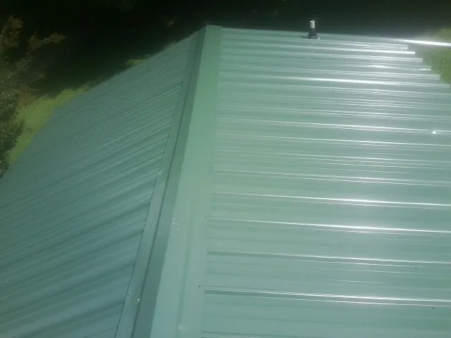New green metal panels meeting at the ridge of a roof — Flat Roof Repair work by our crew in Fairfield